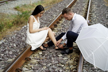 The couple of lover tank photo on the rail track. Woman legs hurt, sitting on the tracks with lovers.