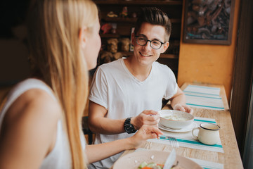 Happy young couple in love having a nice date in a bar or restaurant. They telling some stories...