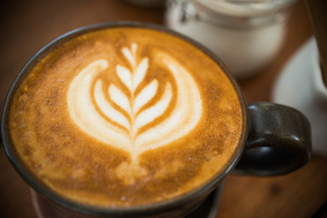 selective focus of latte art foam pattern on top of cappuccino coffee cup for coffee break time