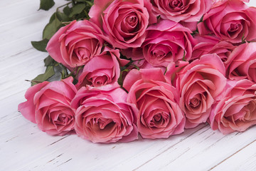 Pink roses bouquet on white wooden background.