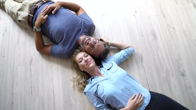 Upper view of couple laying on wooden floor at home