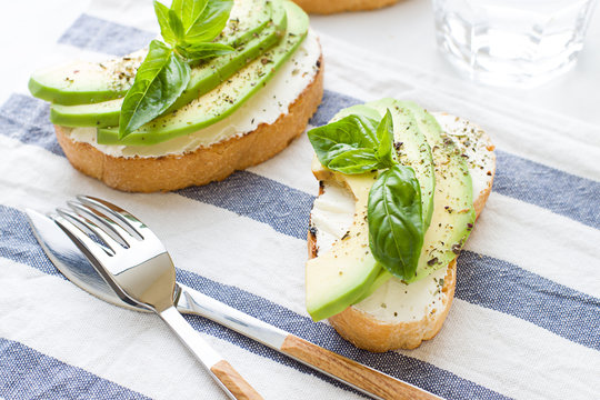 Bruschettas with cream cheese, avocado and basil. Close up