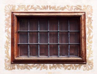 beautiful old window with varnished window and iron bars with a painted motif border on a white distressed cracked wall