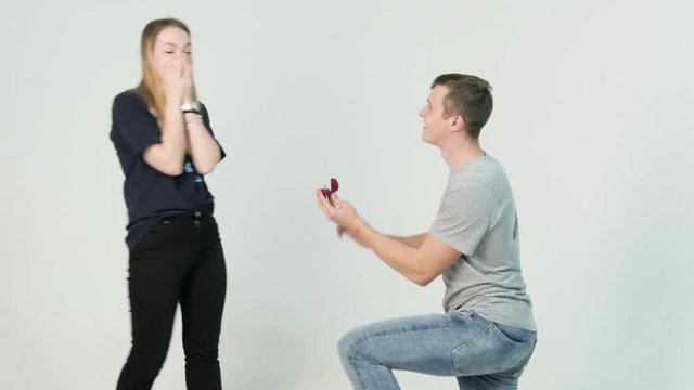 Young man making marriage proposal to his girlfriend. Man is kneeling to the young woman proposing to the girl to get married on white background