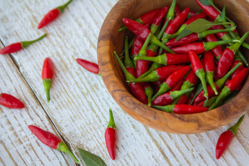 Red hot chili peppers in the bowl and sprinkled on a wooden table