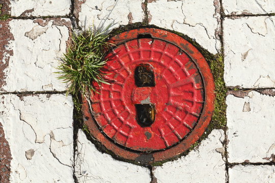 Alter Hydrantdeckel, roter Hintergrund