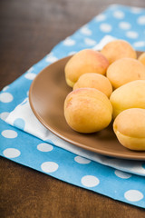 Apricots in a plate on a wooden table.
