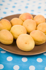 Apricots in a plate on a wooden table.
