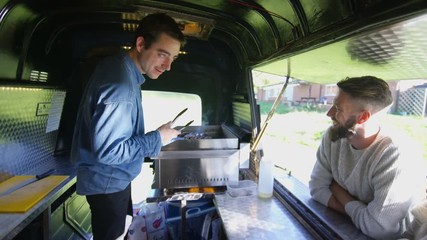  Cheerful food vendor in burger van serving customers at summer festival