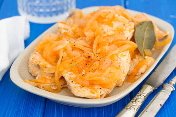 turkey with onion on dish on wooden background