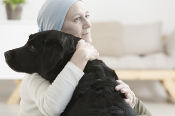 Sick woman hugging dog - obrazy, fototapety, plakaty