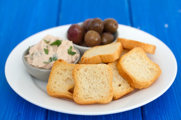 toasts with fish pate and olives on white plate