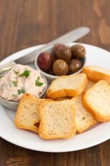 toasts with fish pate and olives on white plate
