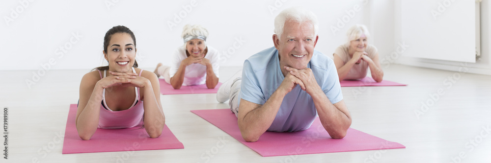 Wall mural Seniors stretching on yoga mats