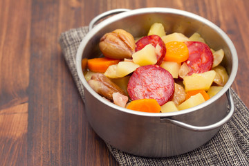  soup chestnuts with smoked sausage in pot on wooden background