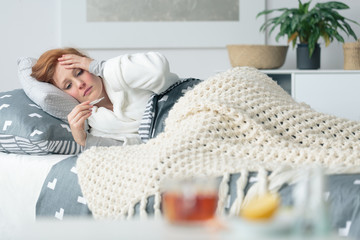 Ill woman looking at thermometer