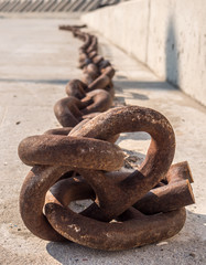 Big stretched anchor chain llie down on the ground front close focus. Portrait view