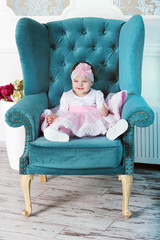 Happy young infant girl sitting in big chair