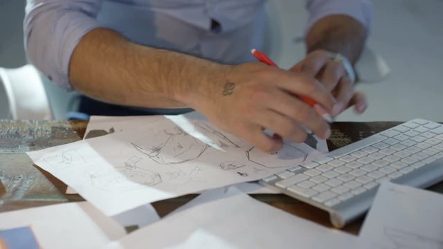 Designer working on a project, sketching and working on computer.