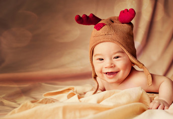 Happy smiling baby dressed in christmas deer hat