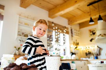 Fototapeta na wymiar Cute little girl in striped dress sitting on kitchen table.
