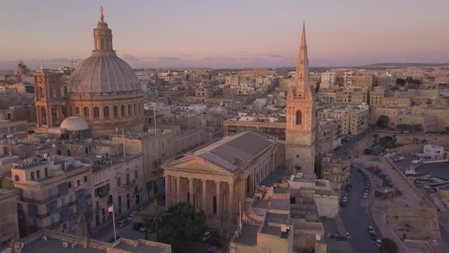 dawn flying towards and around iconic Carmelite church dome and steeple in Valletta Malta