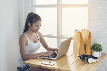 Obraz premium The girl is sitting happily shopping online by the window.