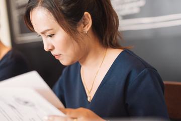 Young Asian woman administrative manager working with financial documentation and financial reports in online database checking in selective focus.