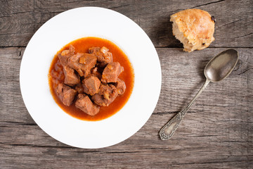 Gulasch mit Zwiebeln und Brot in einem Teller