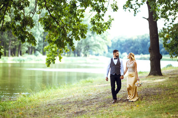 Fototapeta premium Stylish couple of happy newlyweds posing in the park on their wedding day. Perfect couple bride, groom posing and kissing 