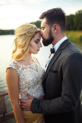 Stylish couple of happy newlyweds posing in the park on their wedding day. Perfect couple bride, groom posing and kissing 
