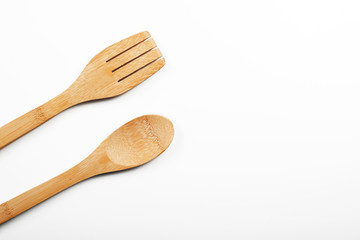 Fork and wooden spoon on white background. Copy space.