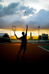 Silhouette of Man Serving a Tennis Ball