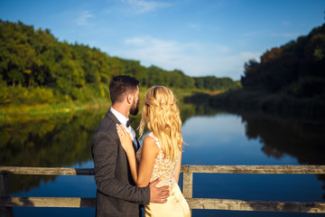 Stylish couple of happy newlyweds posing in the park on their wedding day. Perfect couple bride, groom posing and kissing 
