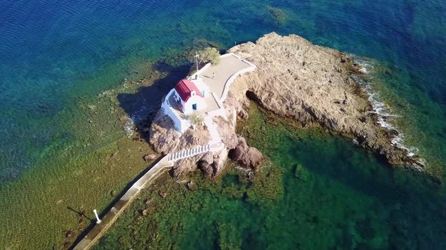August 2017: Aerial drone video of iconic chapel of Agios Isidoros built in a rock next to the coast with clear turquoise waters, Leros island, Aegean, Dodecanese, Greece