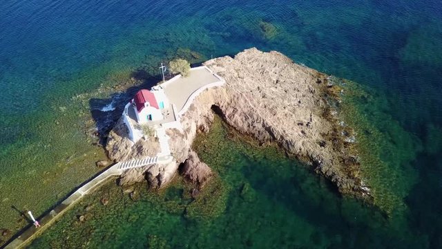 August 2017: Aerial drone video of iconic chapel of Agios Isidoros built in a rock next to the coast with clear turquoise waters, Leros island, Aegean, Dodecanese, Greece