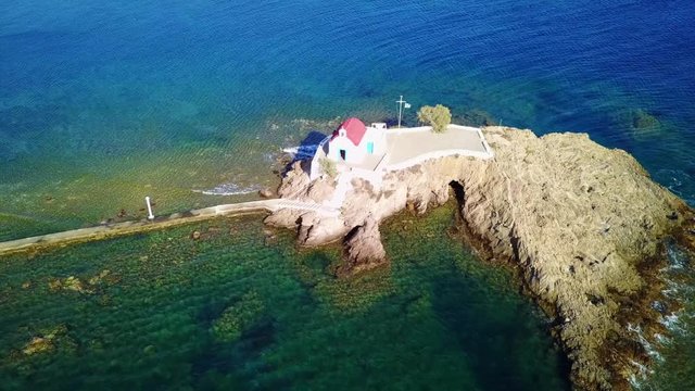 August 2017: Aerial drone video of iconic chapel of Agios Isidoros built in a rock next to the coast with clear turquoise waters, Leros island, Aegean, Dodecanese, Greece