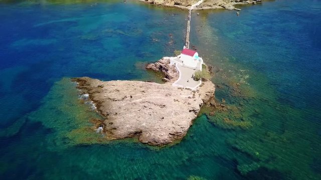 August 2017: Aerial drone video of iconic chapel of Agios Isidoros built in a rock next to the coast with clear turquoise waters, Leros island, Aegean, Dodecanese, Greece