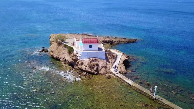 August 2017: Aerial drone video of iconic chapel of Agios Isidoros built in a rock next to the coast with clear turquoise waters, Leros island, Aegean, Dodecanese, Greece