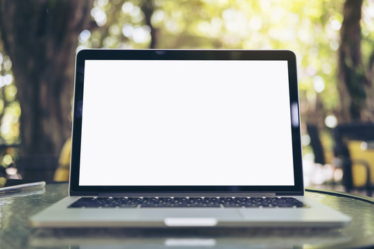 Mockup image of laptop with blank white screen on glass table at outdoor with green nature background