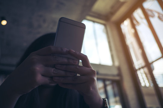 Low angle image of an Asian woman using , looking and holding smart phone cover her face in cafe