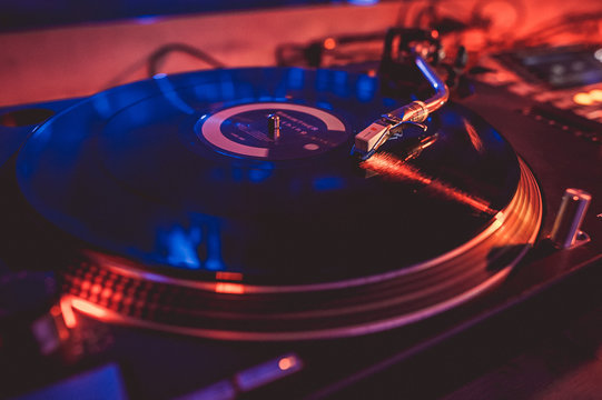 Vinyl record on the turntable in the music club in the light of blue and red light