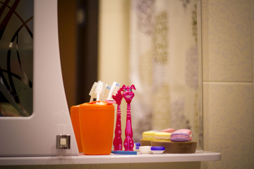 White bath accessories: bar of soap in soap-dish, liquid soap, toothbrushes in the bathroom