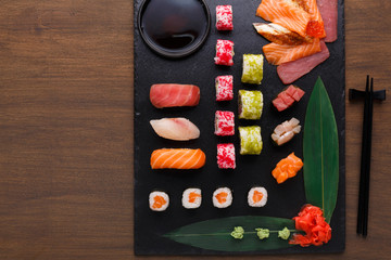 Set of sushi maki and rolls on black rustic wood, top view