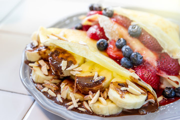 Multi berry crape and banana with chocolate sauce close up.
