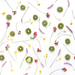 Composition of fruits and flowers. Fruit pattern. Plants and fruits on a white background. Slices of kiwi with green leaves and flowers. Top view. Floral abstract background.	