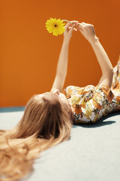 young woman dressing floral pattern jumpsuit in front of an orange wall
