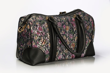 Close Up Shot Of A Unisex Duffle Bag With Multicolor  Floral Pattern and Leather trim And Gold Hardware Isolated On White Background