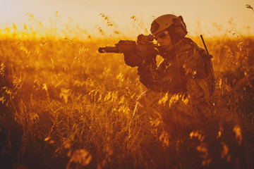 portrait of young soldier face with camouflage against a sunset background