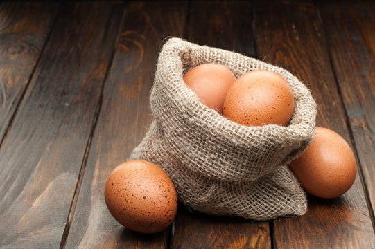 chicken eggs in burlap sack on wooden background